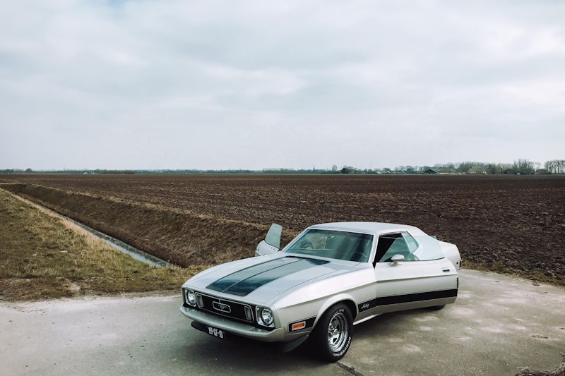 Uniek bovenaanzicht van de complete Ford Mustang huurauto met de portieren uitnodigend open op het Hollandse platteland.