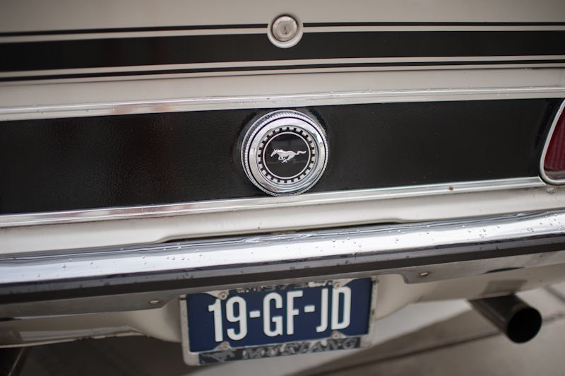 Detail van de achterkant van de V8 Mustang: close-up van het iconische zilveren paardje op de tankdop.