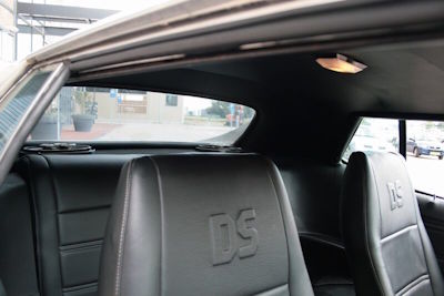 Gedetailleerde blik in het zwarte interieur van de Mustang Grande vanuit het geopende rechter portier, klaar voor een opname of shoot.