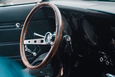 Zijaanzicht van het originele zwarte interieur en het iconische stuur van de Mustang Grande, uitnodigend voor een ontspannen rit door de polder.